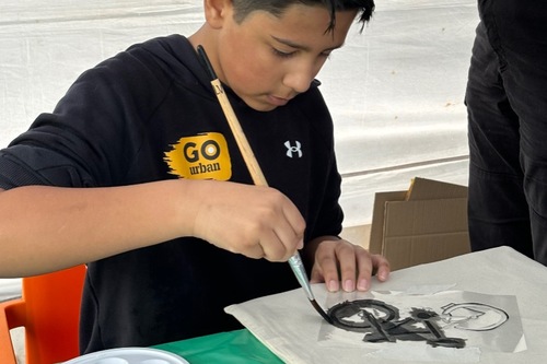 Jongeren beschildert een tas tijdens GO Urban festival op Cruyff Court