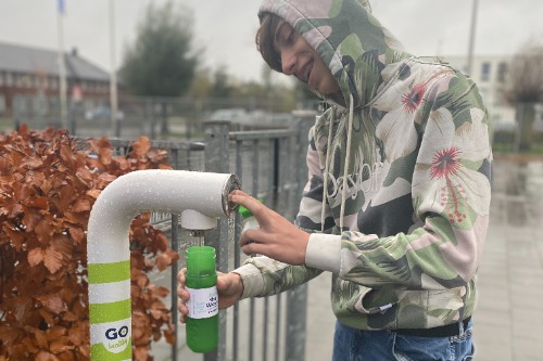 De regen weerhield de leerlingen er niet van om hun drinkwaterfles te vullen bij het nieuwe watertappunt.